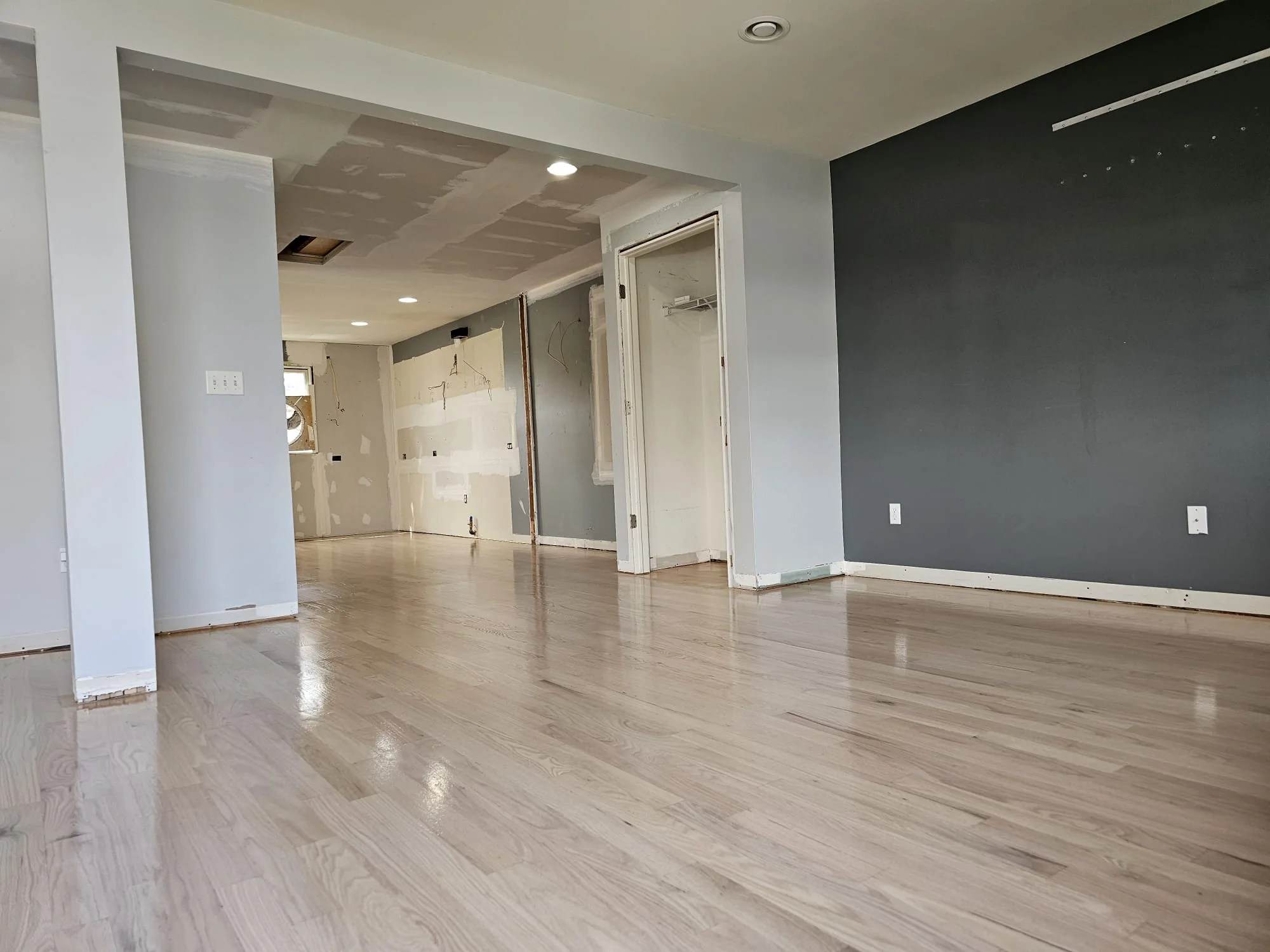 Oak floor running into a room with a dark accent wall